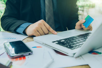 Midsection of man using mobile phone on table