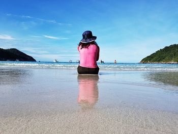 Rear view of woman on beach against sky