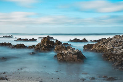 Long exposure with neutral density filter of blurred motion of pacific ocean waves on rocky shore