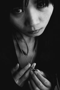 Close-up portrait of young woman showing pendant