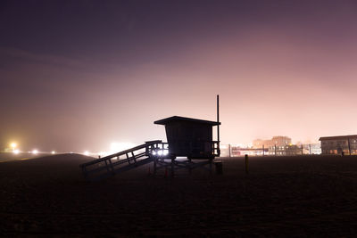 Silhouette hut on beach against sky during sunset