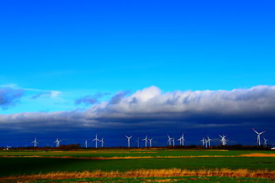 Wind turbines on field against sky