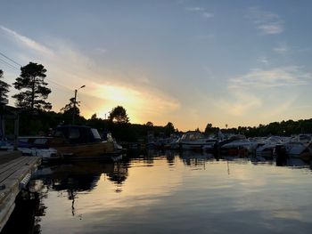 Boats moored at harbor against sky during sunset