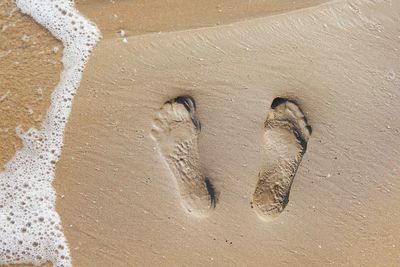 High angle view of footprints on wet sand