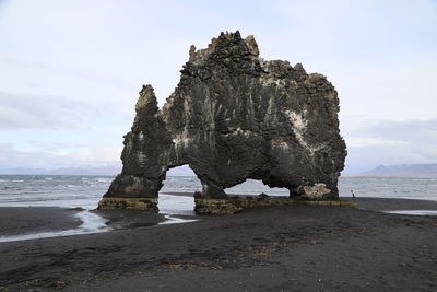 Rock formation on beach against sky