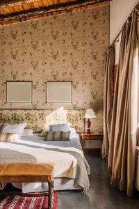 Interior of stylish bedroom with comfortable bed covered with coverlet near window decorated with curtains