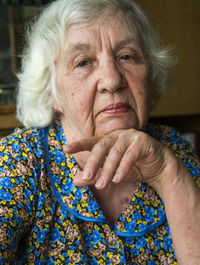 Close-up portrait of woman sitting with hand on chin at home