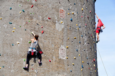 Low angle view of man and woman climbing on wall