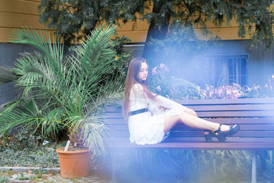 Full length of young woman sitting on bench at park