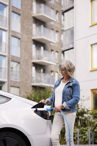 Senior woman charging electric car