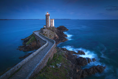 Lighthouse by sea against sky