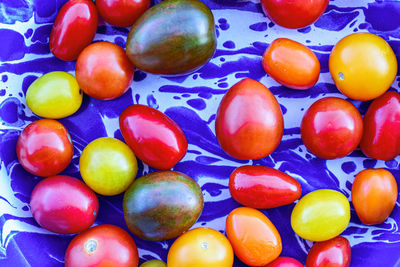 Yellow, red, orange, and dark green heirloom cherry tomatoes on blue spatter enamelware plate