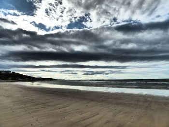 Scenic view of beach against cloudy sky