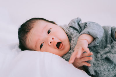 Close-up of cute baby boy lying on bed