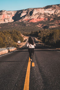 Rear view of woman running on road