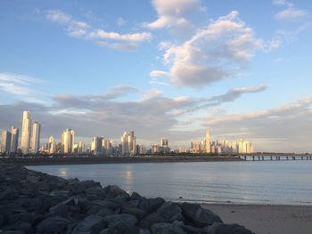 Sea by city buildings against sky