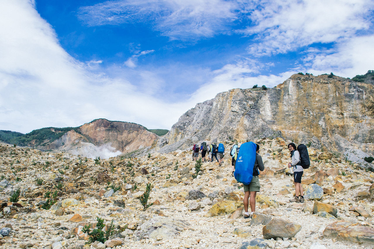 mountain, sky, leisure activity, lifestyles, men, rear view, rock - object, full length, hiking, cloud - sky, rock formation, landscape, tranquility, person, scenics, nature, tranquil scene, standing