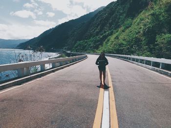 Full length of woman standing on road against mountain