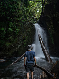 Rear view of man standing against waterfall