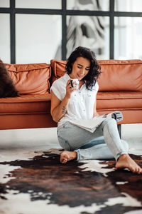 Woman reading magazine while having coffee at home