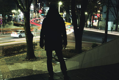 Rear view of woman standing on street at night