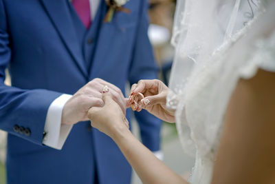 Midsection of bride exchanging wedding ring