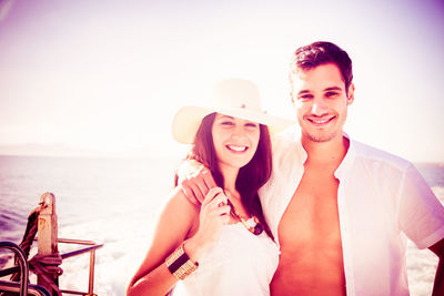 Portrait of young couple standing against sea