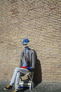 Man sitting against brick wall