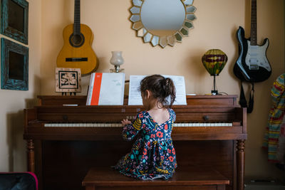 Girl playing piano, cute child preschool practicing musical instrument