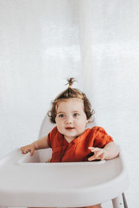 Cute girl sitting on baby stroller at home