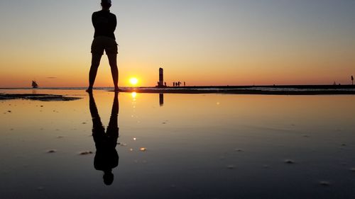 Silhouette man standing on beach against sky during sunset