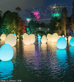 Reflection of illuminated trees in swimming pool at night