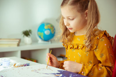 Cute girl painting while sitting at home