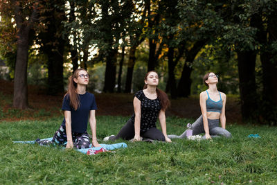 The relaxed girls is doing yoga in the park on carpet