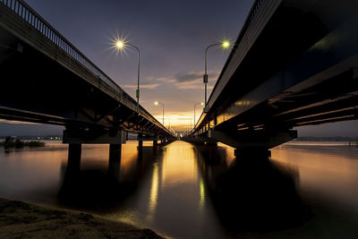 Low angle view of bridge over river against sky at night