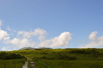 Scenic view of grassy field against cloudy sky