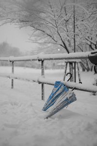 Empty bench on snow covered field during winter