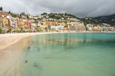 The beautiful beach of menton with turquoise water and beautiful colorful houses in the background