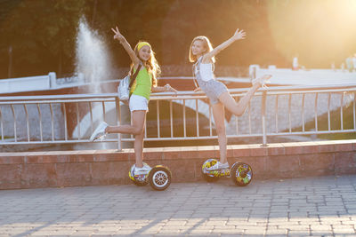 Full length portrait of female friends hovering on hoverboards at park