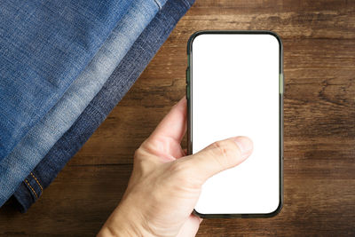 Close-up of hand holding mobile phone on table