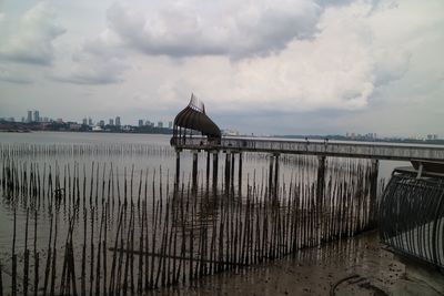 Built structure by sea against cloudy sky