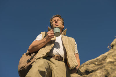 Low angle view of man standing against blue sky