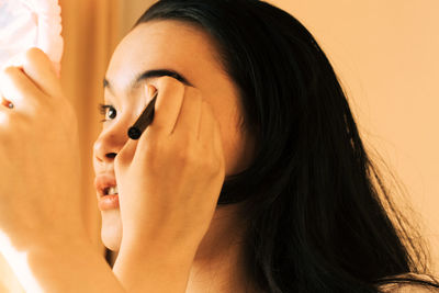 Close-up of woman applying make-up at home