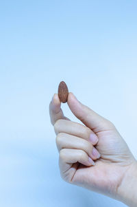 Close-up of hand holding ice cream against blue background