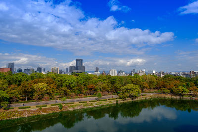 Scenic view of lake by buildings against blue sky