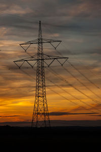 Low angle view of silhouette electricity pylon against sky during sunset