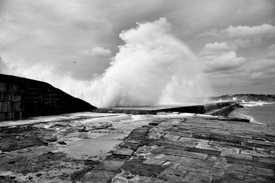 Wave splashing at fort de socoa against cloudy sky