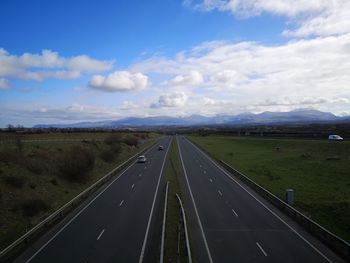 Road passing through land against sky