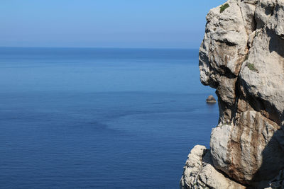 Rock formation in sea against blue sky