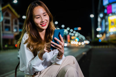 Young woman using mobile phone at night